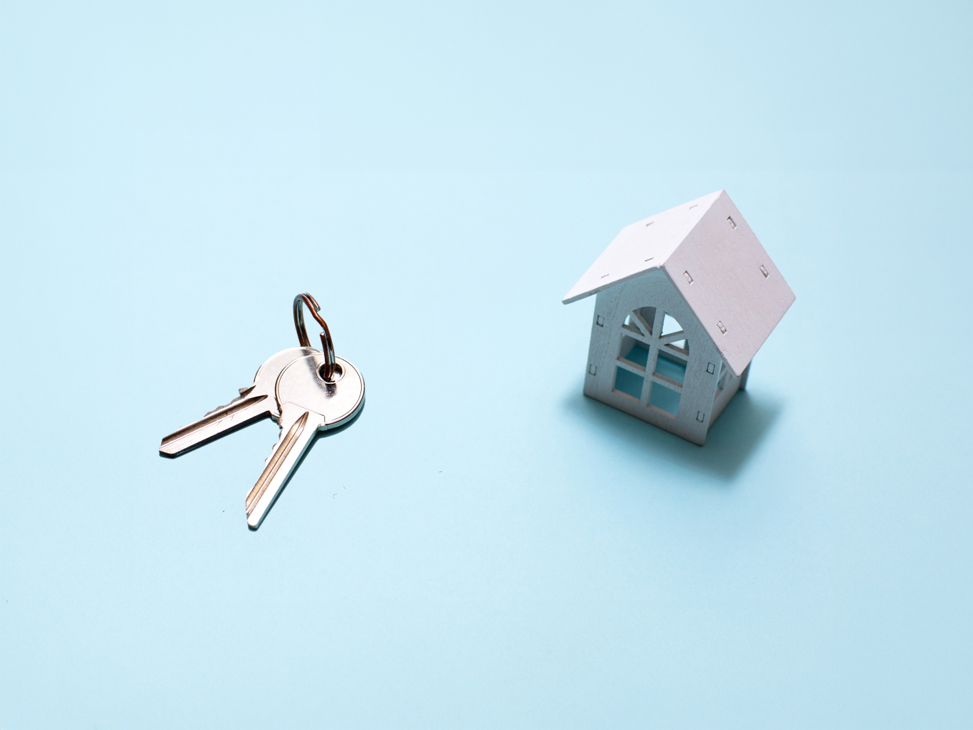 White wooden house symbol and keys on blue.