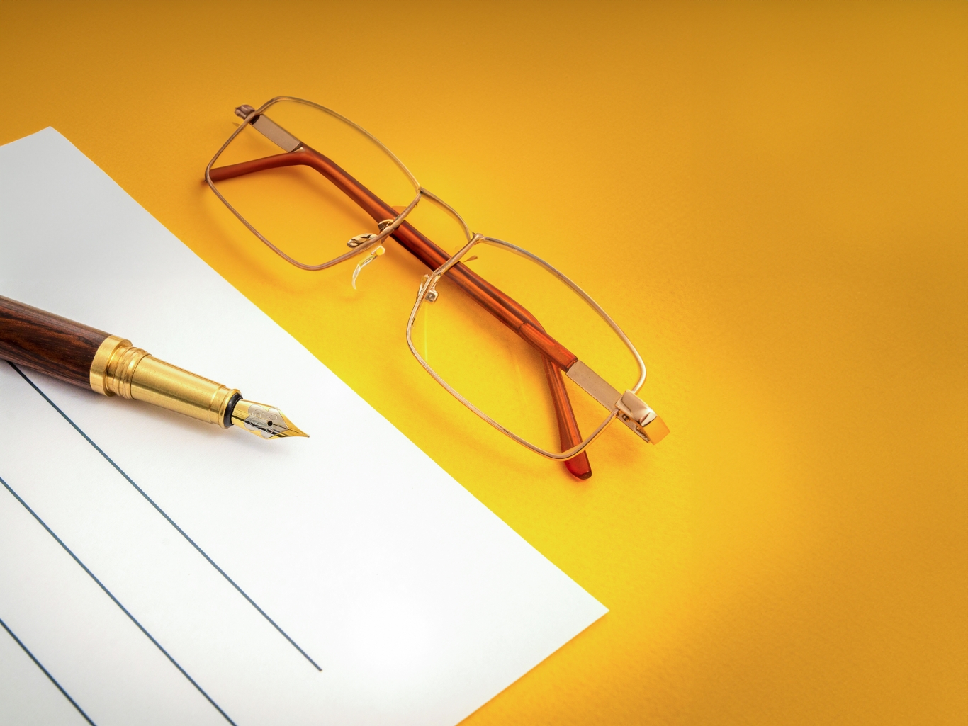 Law office still life with a pen, piece of paper and some glasses on a yellow background.