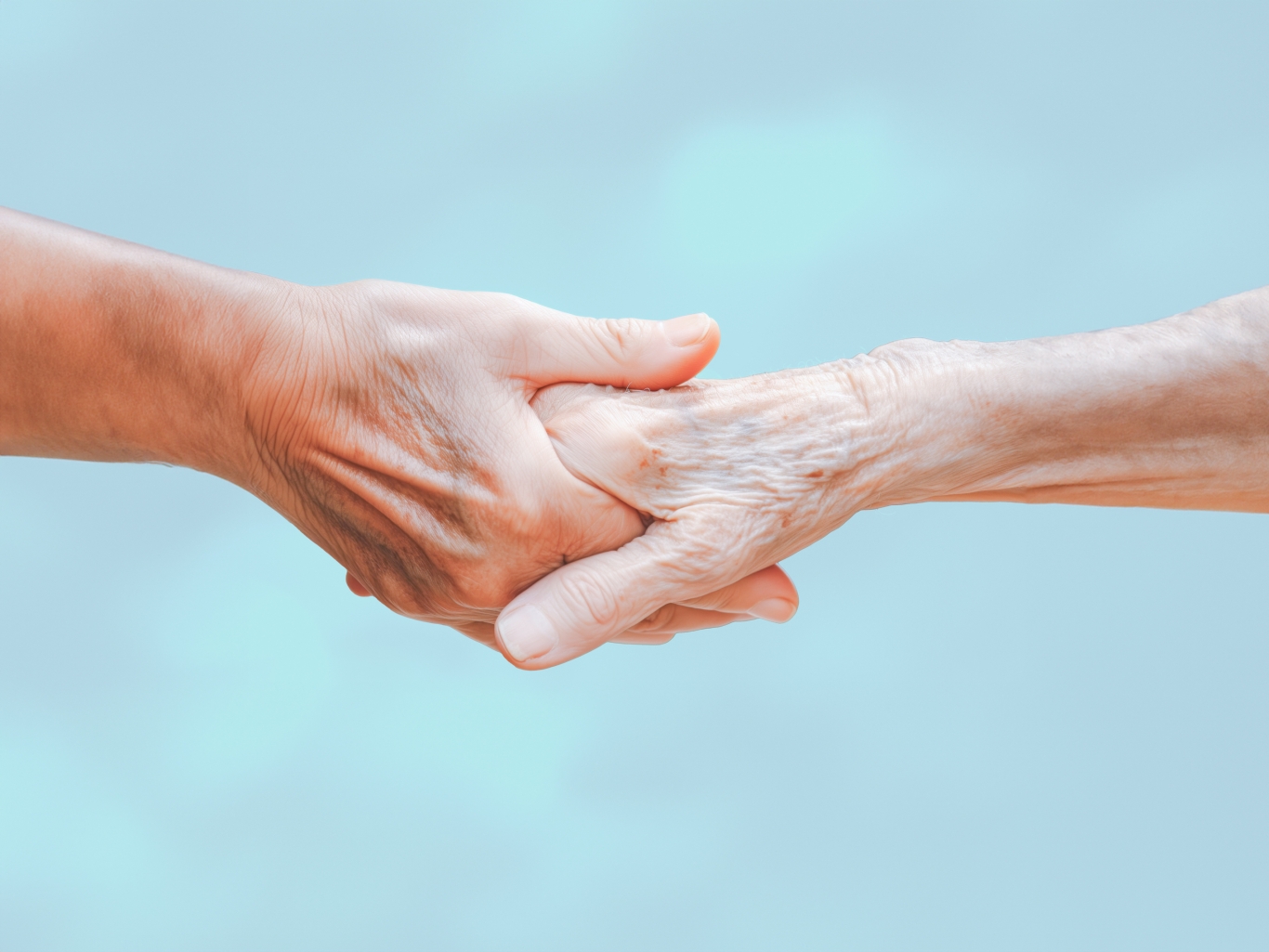 Young hand holding an older persons hand in a caring way.